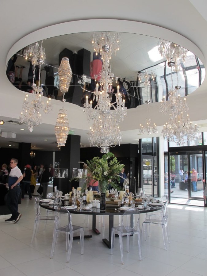 photo of the showroom with table settings and large crystal chandeliers hanging from a mirrored ceiling