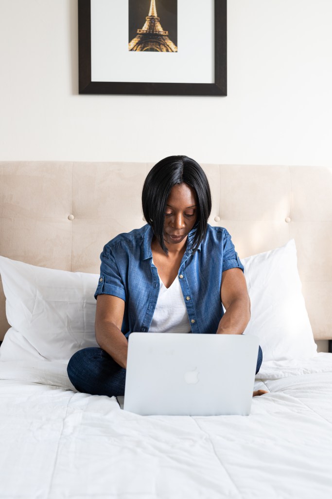 Woman sitting on a bed working on a laptop
