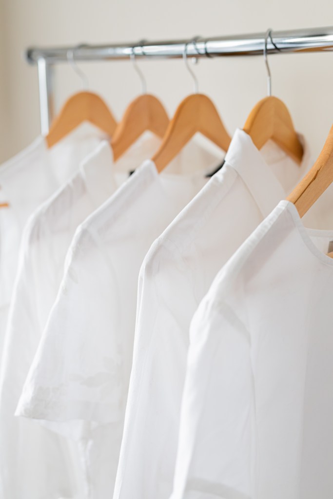 A small selection of white clothing hanging on wooden hangers