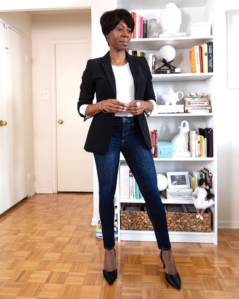 black woman wearing dark wash blue skinny jeans, black heels, a black blazer and white t-shirt