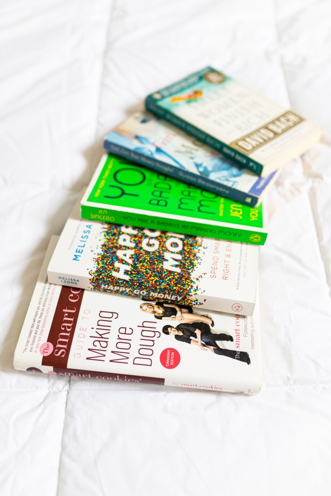 a small collection of personal finance books fanned out on a bed