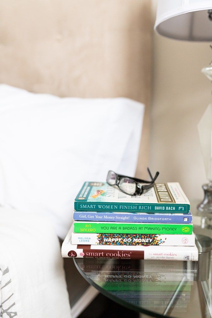 stack of personal finance books on a night table in a bedroom