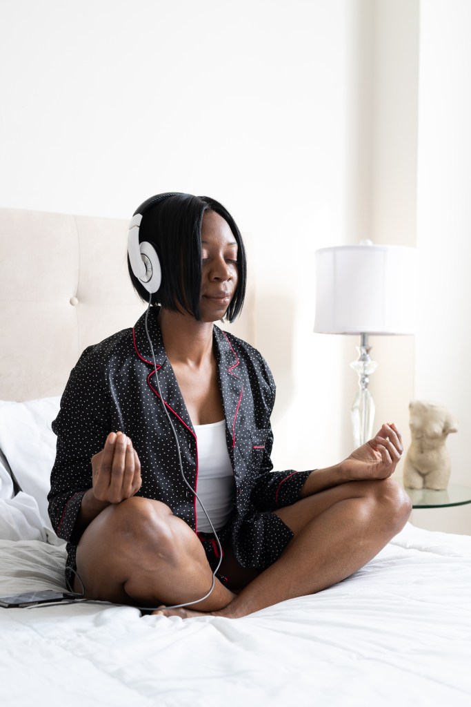 Cassandra, sitting on a bed, meditation with headphones